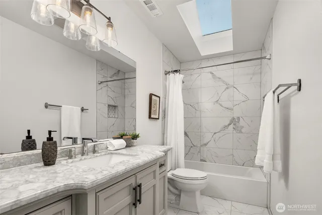 a bathroom with a granite countertop sink a toilet and shower