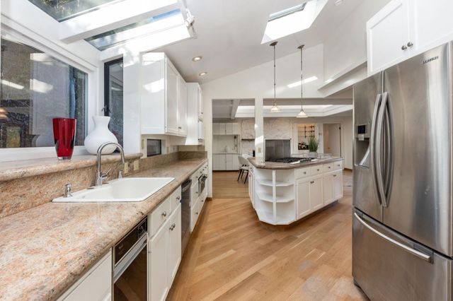 a kitchen with stainless steel appliances granite countertop a stove oven and a granite counter tops with white cabinets