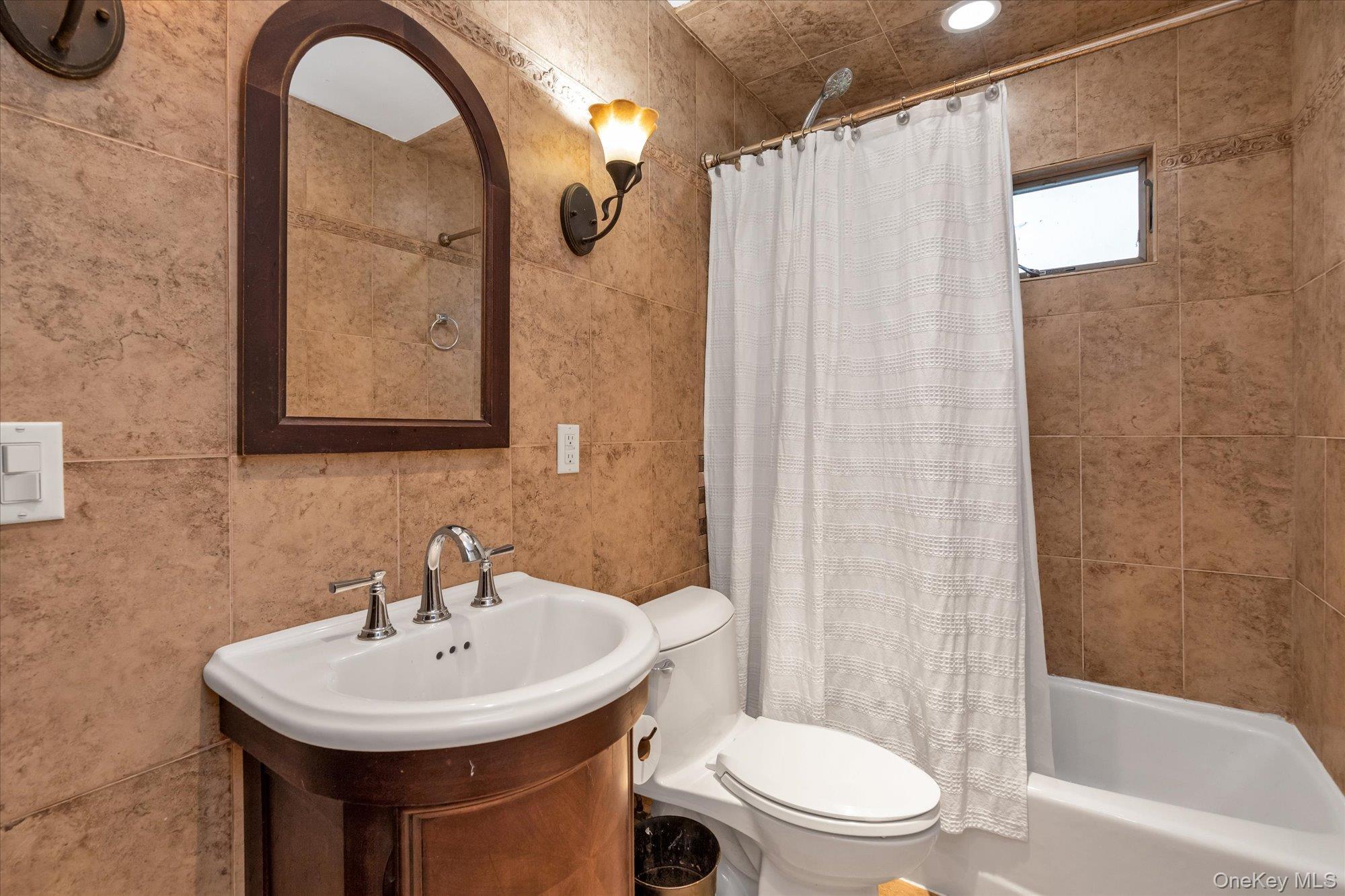 26 Cheshire Road Inwood, NY 11096 - Photo 12 of 22 Full bath featuring tile walls, shower / bath combo with shower curtain, and vanity