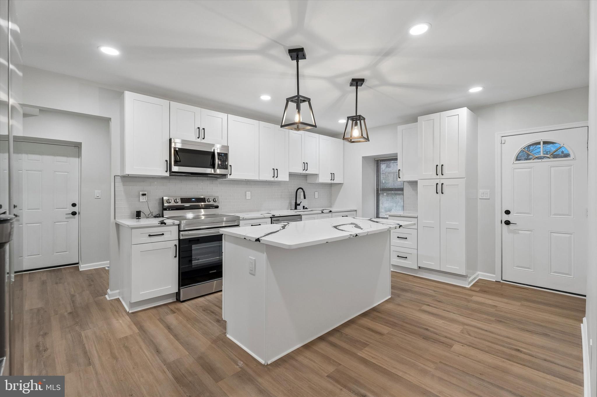 4359 Fleming Street Philadelphia, PA 19128 - Photo 17 of 43 a kitchen with stainless steel appliances a white stove top oven a sink dishwasher and a refrigerator with wooden floor