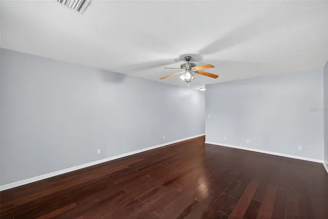 a view of an empty room with wooden floor and chandelier