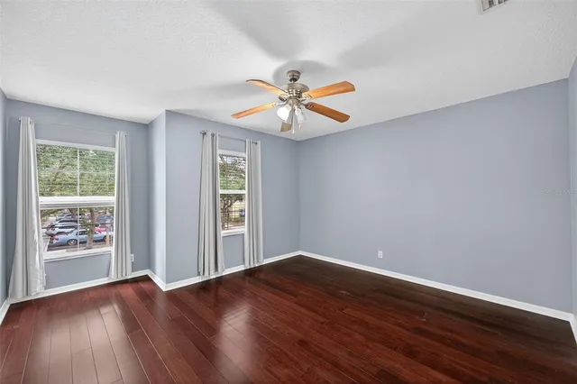 a view of a room with wooden floor and a ceiling fan