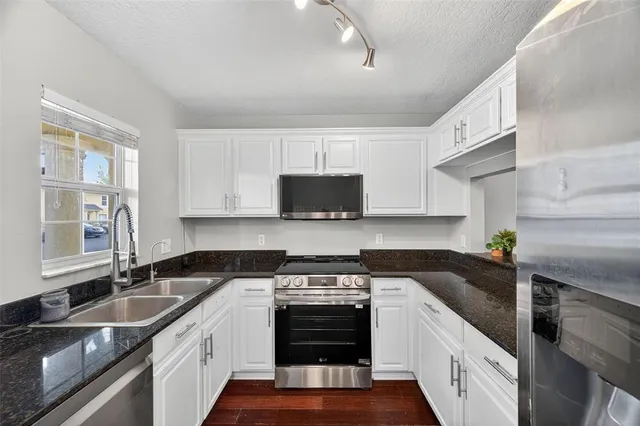 a kitchen with stainless steel appliances granite countertop a sink stove and refrigerator