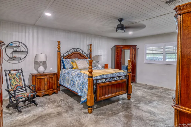 a bedroom with a bed a dresser and windows