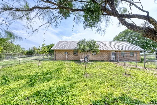 a view of a house with a yard and a large tree