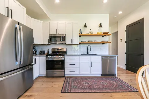 a kitchen with granite countertop a refrigerator and a stove top oven