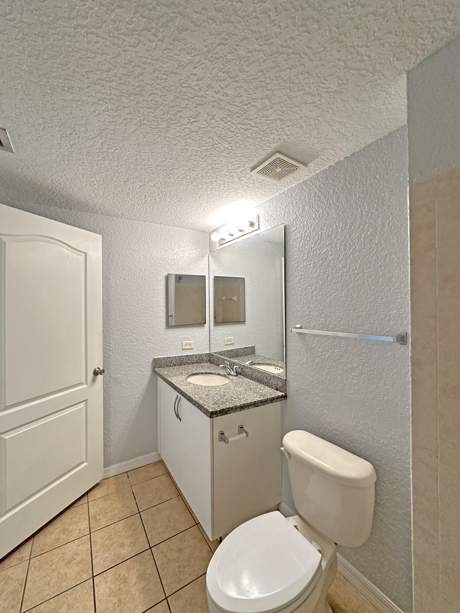 144 Southwest Peacock Boulevard, Unit 101 Port St. Lucie, FL 34986 - Photo 25 of 52 a bathroom with a granite countertop toilet sink and mirror