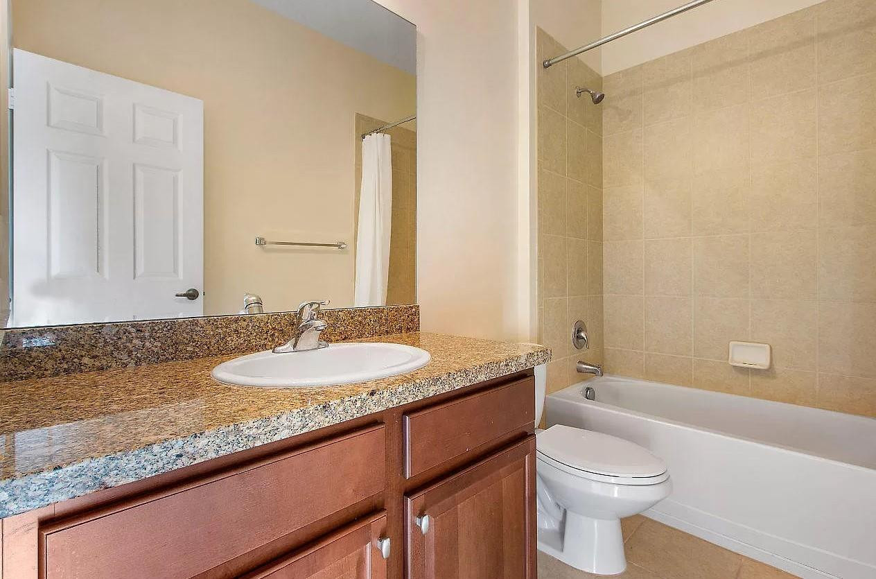2851 Prospect Road Tamarac, FL 33309 - Photo 16 of 21 a bathroom with a granite countertop sink a toilet and a bathtub