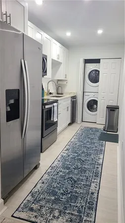 a kitchen with stainless steel appliances granite countertop a refrigerator a stove and a sink with wooden floor