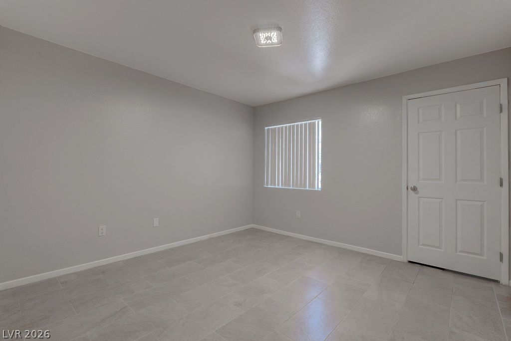 7885 West Flamingo Road, Unit 1016 Las Vegas, NV 89147 - Photo 14 of 24 A well-lit bedroom with fresh gray walls and durable tile flooring, ready for personalization.