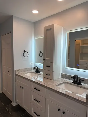 a bathroom with a granite countertop double vanity sink and mirror