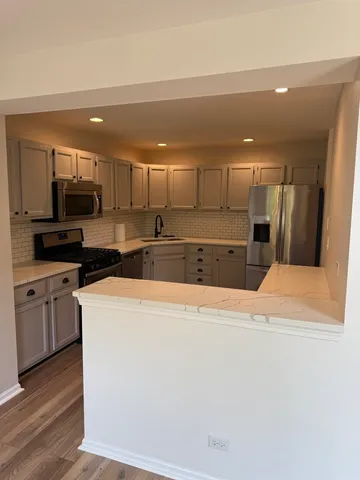 a large kitchen with stainless steel appliances kitchen island granite countertop a refrigerator a stove a sink and a microwave