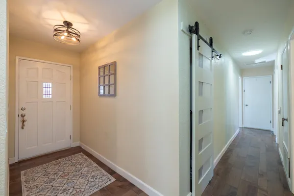 a view of a hallway with a chandelier fan and a bathroom