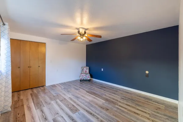 a view of a big room with wooden floor and a chandelier fan