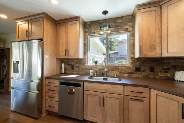 a kitchen with stainless steel appliances granite countertop a refrigerator a sink and white cabinets