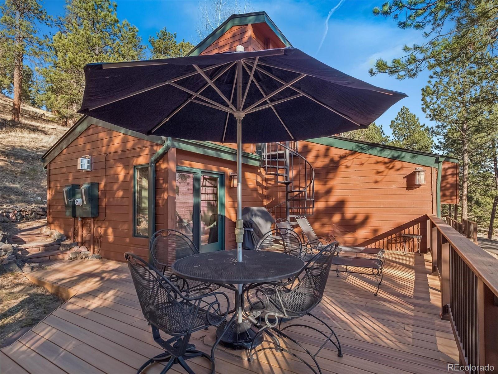 67 Oak Way Evergreen, CO 80439 - Photo 13 of 44 a view of patio with table and chairs under an umbrella