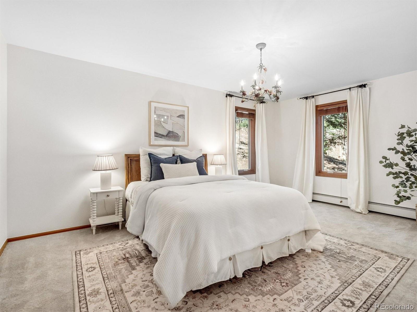 67 Oak Way Evergreen, CO 80439 - Photo 34 of 44 a bedroom with a large bed and a chandelier