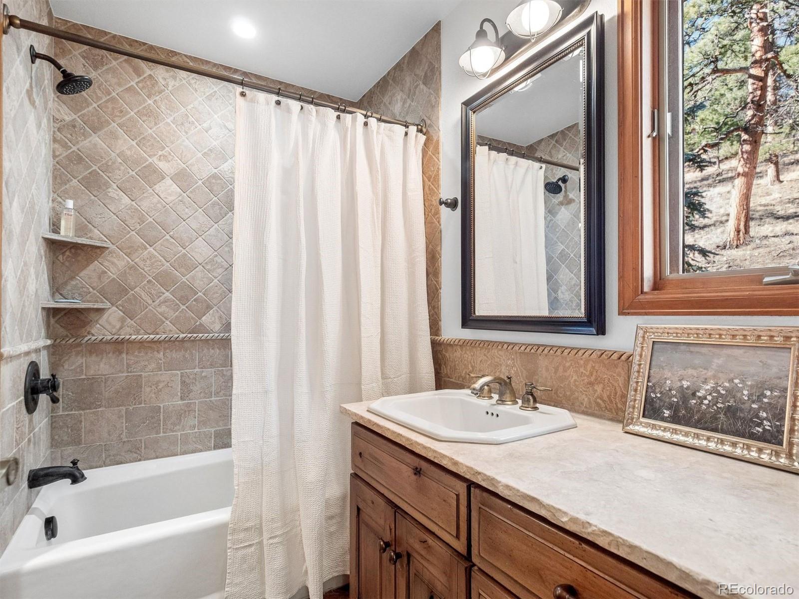 67 Oak Way Evergreen, CO 80439 - Photo 35 of 44 a bathroom with a granite countertop sink a mirror and a shower