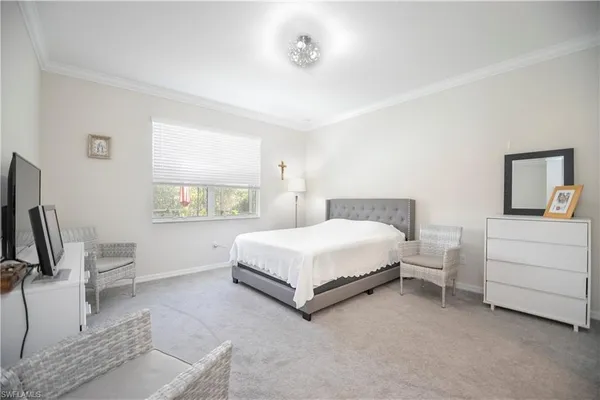a bedroom with a bed lamp on desk and a window