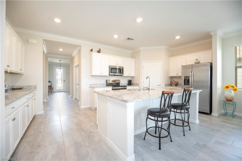 2075 Parson Street Naples, FL 34120 - Photo 5 of 15 a kitchen with stainless steel appliances kitchen island granite countertop a refrigerator a stove top oven a sink dishwasher and white cabinets with wooden floor