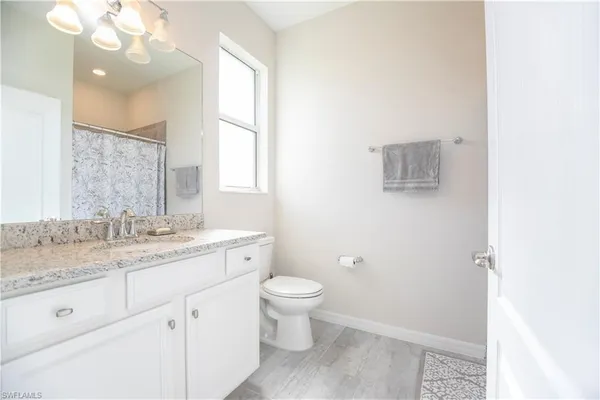 a bathroom with a granite countertop sink a toilet and a mirror