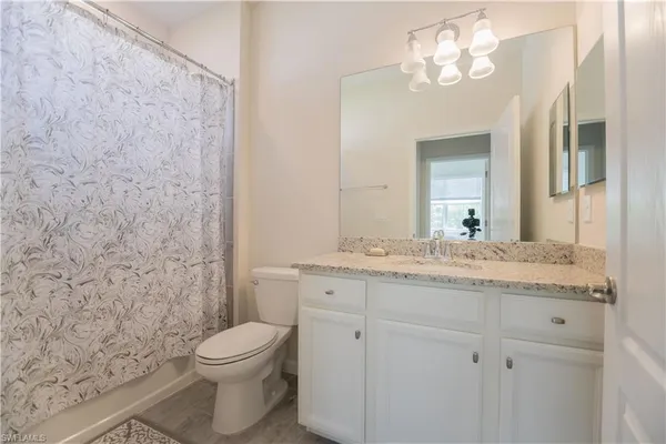 a bathroom with a granite countertop toilet a sink and a mirror
