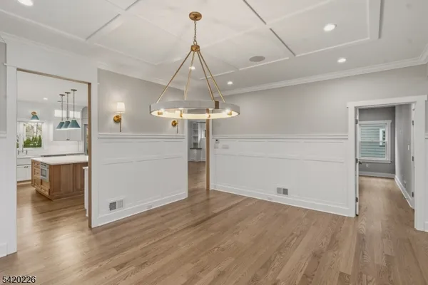 a view of an empty room with wooden floor and a kitchen