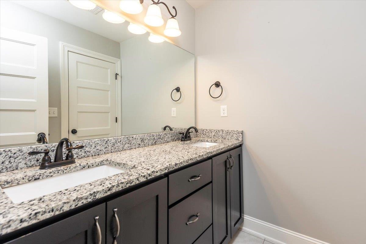 3328 Straw Bridge Road Olive Branch, MS 38654 - Photo 28 of 28 Double vanity with integrated sinks, granite countertops, dark wood-finish cabinetry, and oil-rubbed bronze fixtures