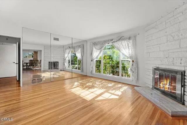 a view of an empty room with wooden floor fireplace and a window