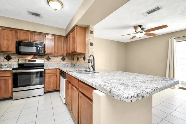 a kitchen with kitchen island granite countertop a sink stainless steel appliances and cabinets