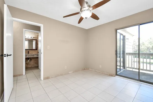 an empty room with chandelier fan and windows
