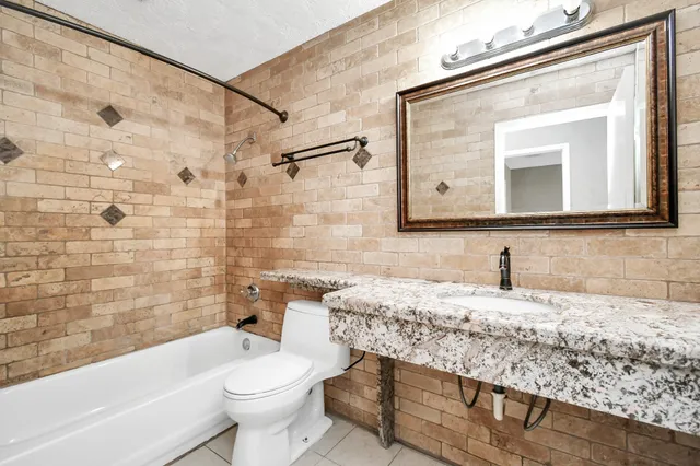 a bathroom with a granite countertop sink a toilet and bathtub