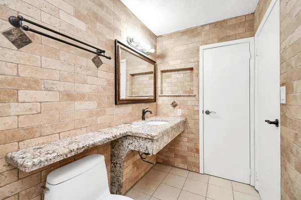 a bathroom with a granite countertop sink a mirror and shower