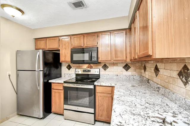 a kitchen with stainless steel appliances granite countertop a refrigerator stove and microwave