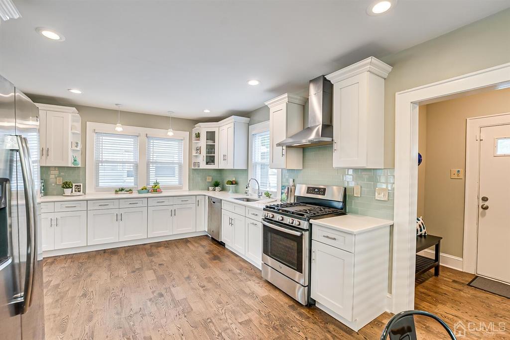 79 Van Ness Terrace Maplewood, NJ 07040 - Photo 16 of 40 a kitchen with a stove a sink dishwasher a refrigerator and white cabinets with wooden floor