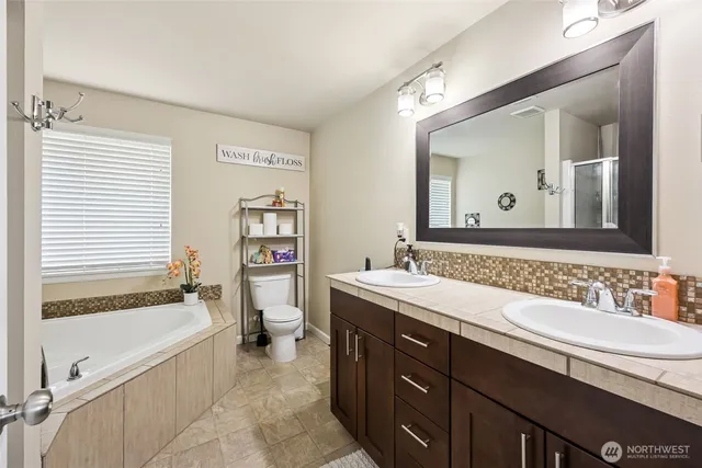 a bathroom with a tub double sink window and mirror