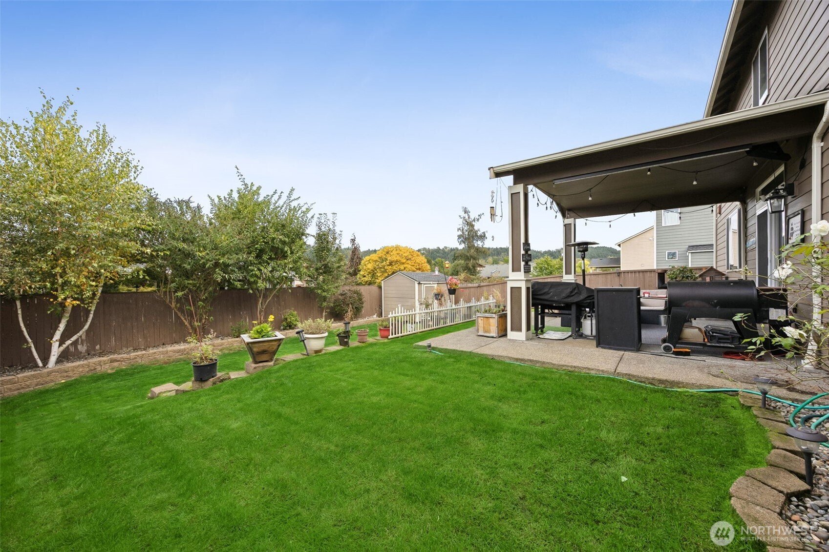 103 Balmer Street Southwest Orting, WA 98360 - Photo 3 of 30 a view of a backyard with table and chairs under an umbrella next to a yard