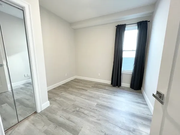 an empty room with wooden floor and mirror