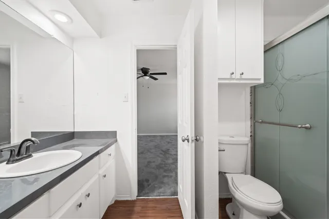 a bathroom with a granite countertop sink a toilet and shower