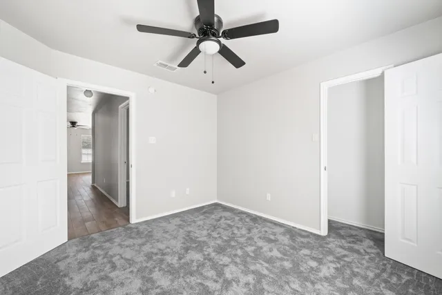 an empty room with a ceiling fan and carpet