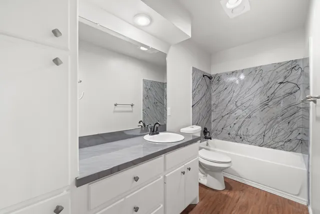 a bathroom with a granite countertop sink a toilet and bathtub