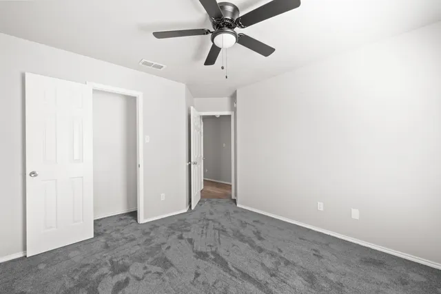 an empty room with a ceiling fan and a window
