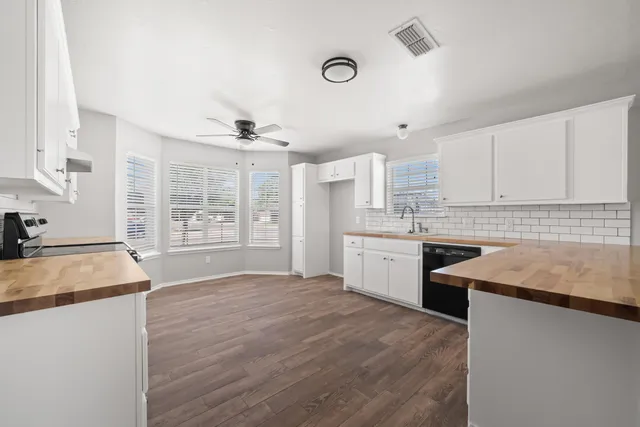 a kitchen with granite countertop a sink stainless steel appliances and white cabinets