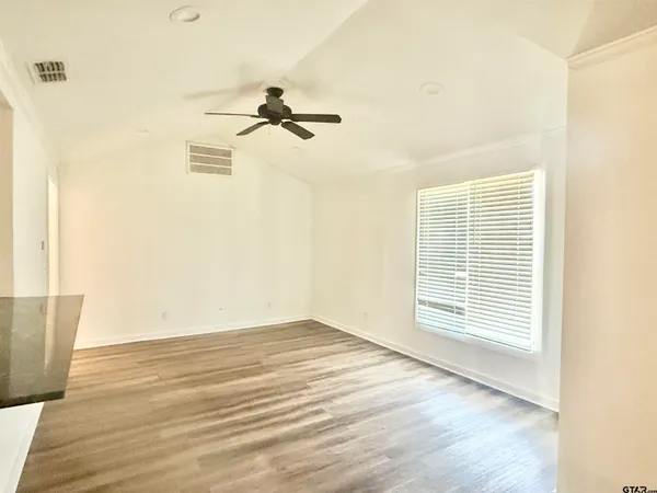 a view of empty room with wooden floor and fan