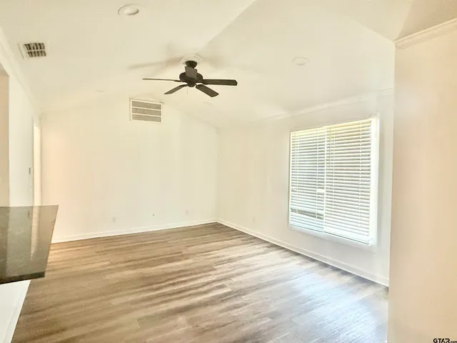 a view of empty room with wooden floor and fan