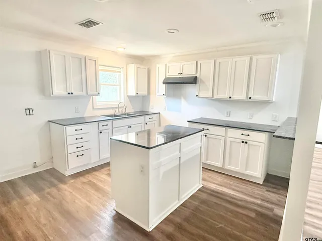 a kitchen with white cabinets sink and stove