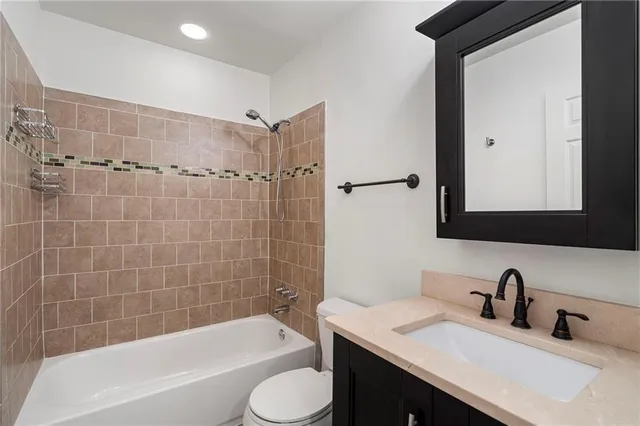 a bathroom with a granite countertop sink toilet and shower