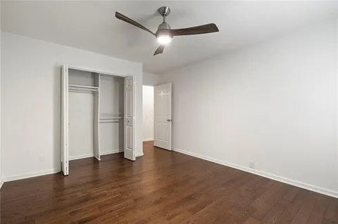 an empty room with wooden floor and ceiling fan