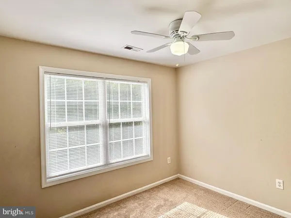 a view of an empty room with window and chandelier fan