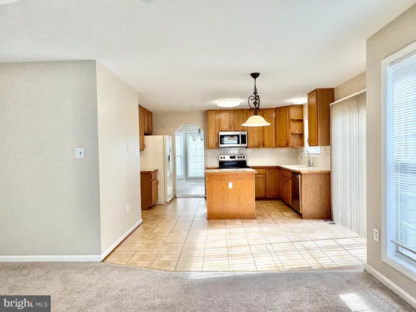 a large kitchen with stainless steel appliances kitchen island granite countertop a refrigerator a sink dishwasher a stove with white cabinets and countertops